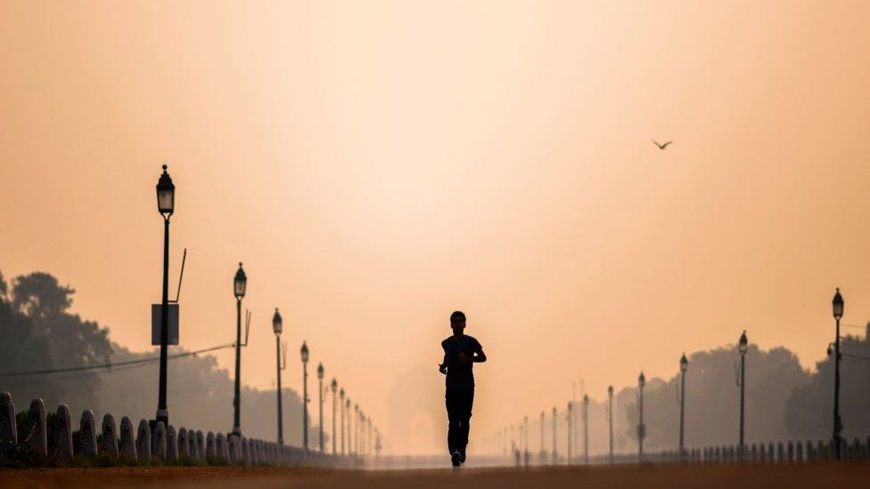 A man jogs along Rajpath street during a smoggy morning in New Delhi on October 15, 2020