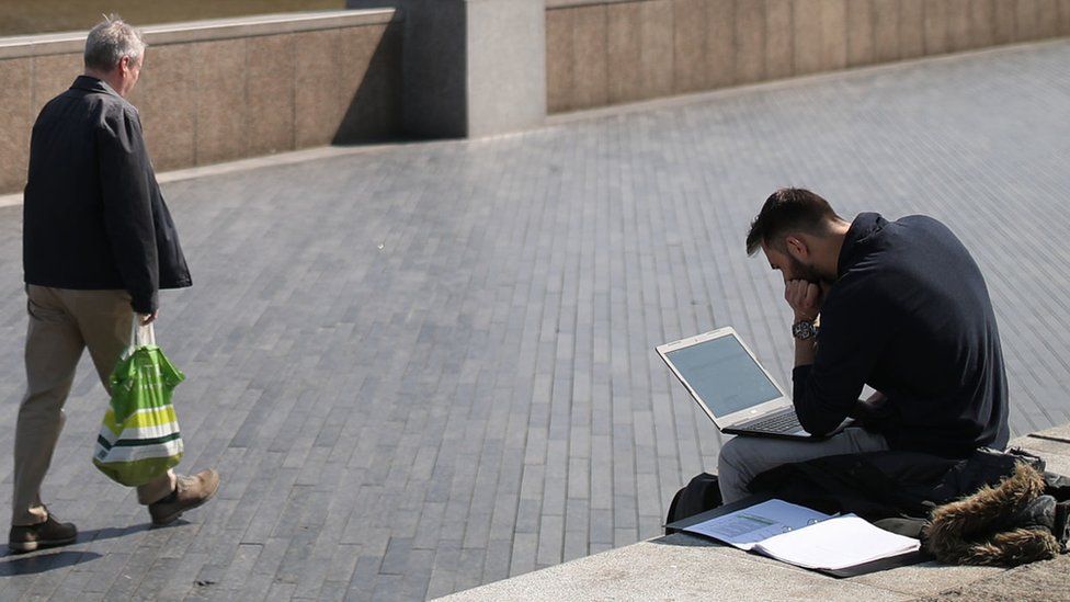 Мужчина работает за ноутбуком на берегу Темзы в Лондоне