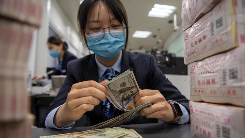 a woman in China counts dollar bills