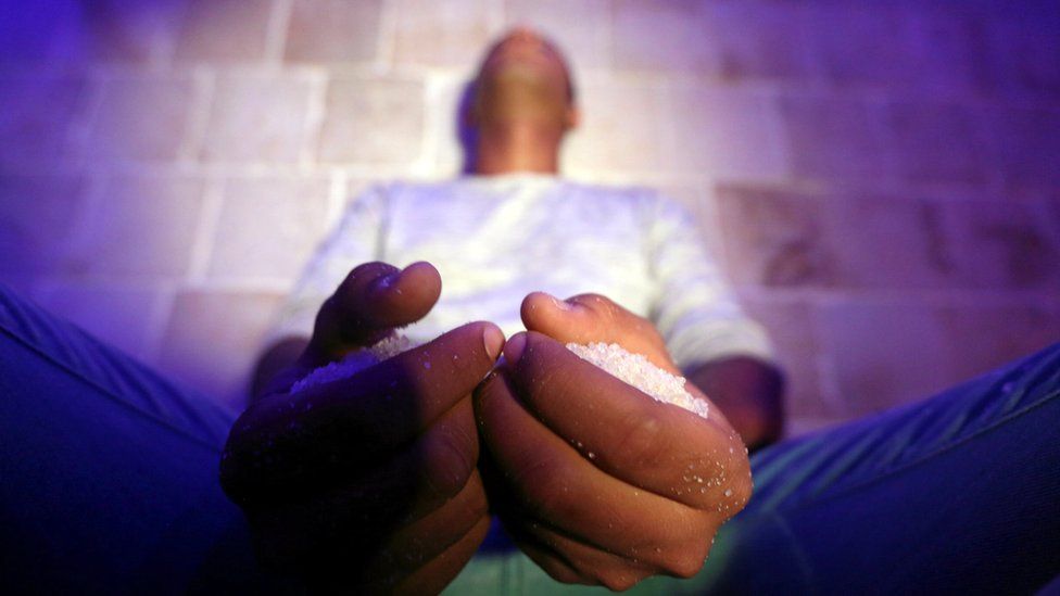 Closeup of man with two handfuls of salt in the meditation position.