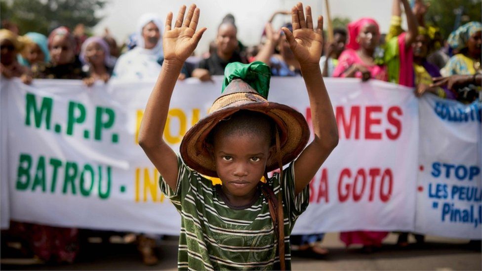 A Fulani boy protests in front of a sign saying "Stop the Genocide" during a silent march orhanized by the Mouvement Peul et allies pour la paix, an organisation of ethnic Fulani people on June 30, 2018 in Bamako in response to a massacre in Koumaga, Mali. On June 23, at least 300 Christian farmers were killed and ten are missing following an attack in central Mali, believed to have been carried out by Muslim Fulani hunters