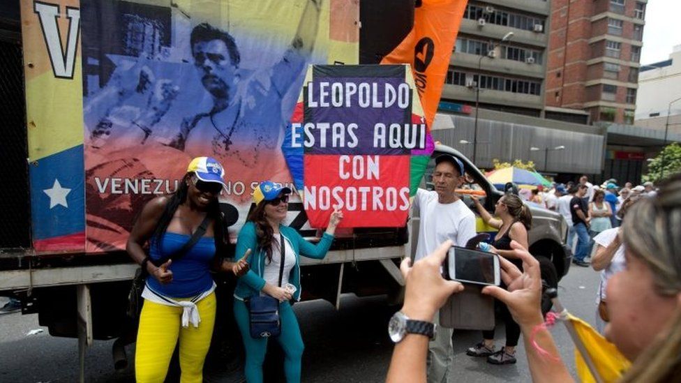 Opposition members pose for a photo next to a poster of jailed opposition leader Leopoldo Lopez at a rally in Caracas on 19 September, 2015