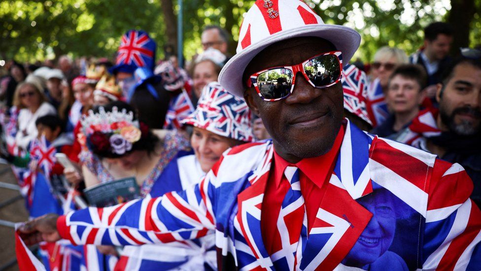 A man wearing a Union Jack suit looks on as people gather along The Mall for the Queen's Platinum Jubilee celebrations in London
