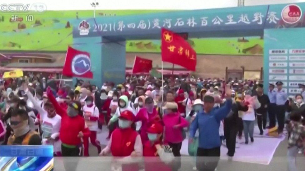 A large crowd of ultramarathon runners waving flags as they set off before disaster struck in Gansu, China on 22 May 2024