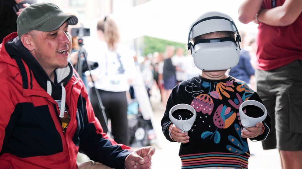 Child using a VR headset while a man looks on.
