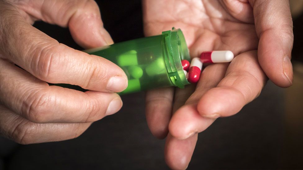 A person empties pills from a bottle into their hand