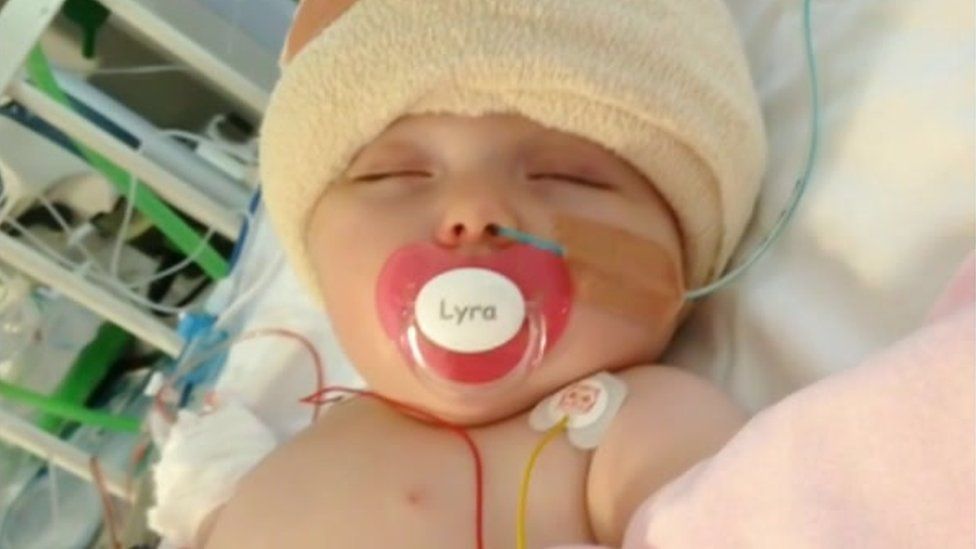 Image of Lyra as a baby in a hospital bed