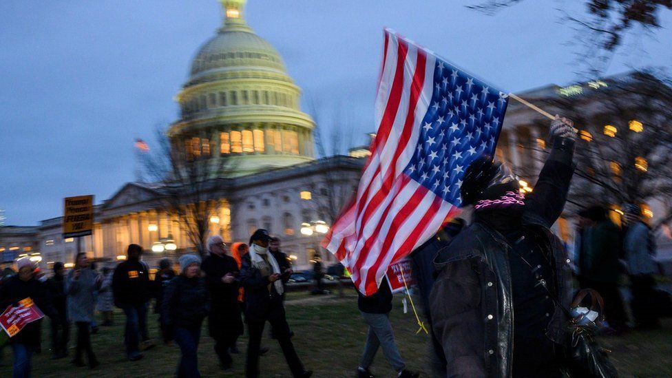A protester waves a US national flag upside down, in a sign of distress, outside the Capitol in Washington, DC