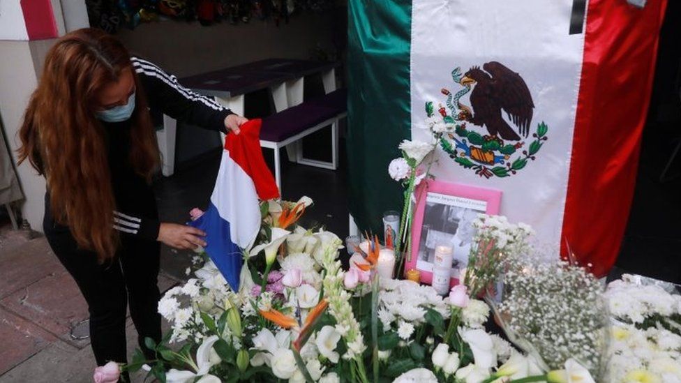 An employee places a French flag on an altar outside a restaurant owned by French businessman Baptiste Jacques Daniel Lormand after he was found murdered, in Mexico City, Mexico, November 30, 2020.