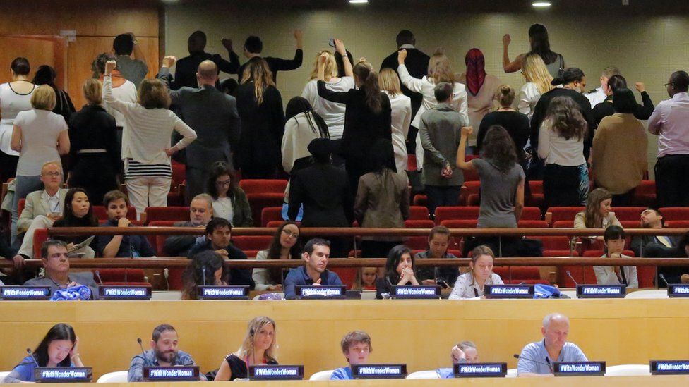 United Nations staff stand and turn their backs in a silent protest during a UN meeting to designate Wonder Woman as an "Honorary Ambassador for the Empowerment of Women and Girls," on 21 October in New York