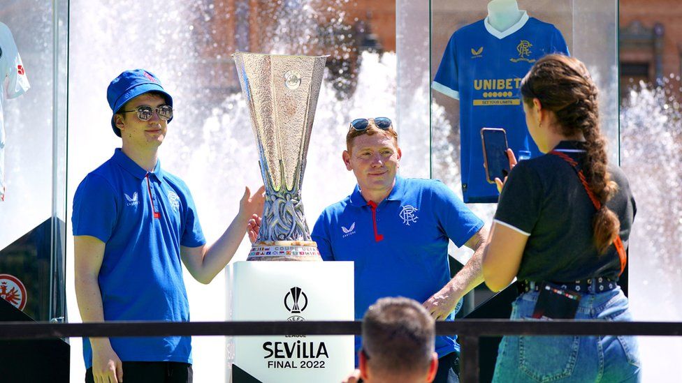 Rangers fans have their photo taken with the UEFA Europa League trophy at the Plaza de Espana in Seville