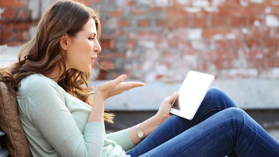 woman blowing a kiss at a tablet
