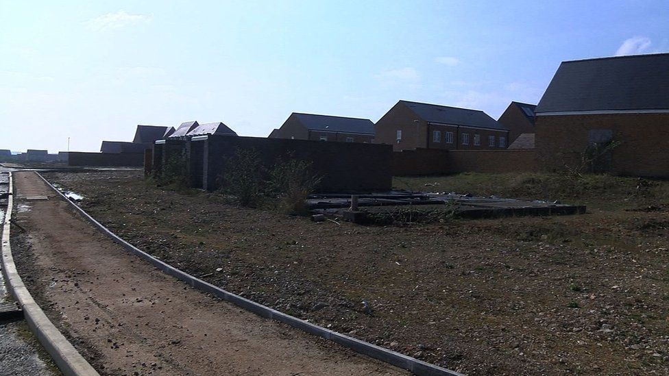 New houses next to an unfinished footpath and unpaved road.
