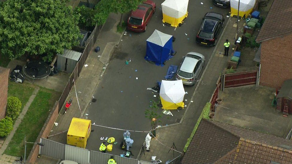 Aerial shot of scene showing four white tents and one blue with police activity
