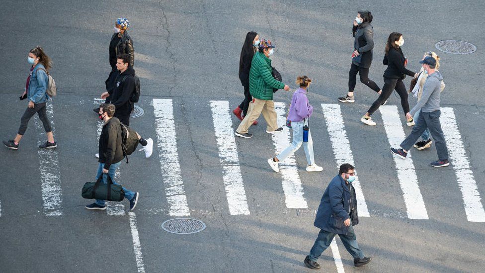 people in masks crossing road
