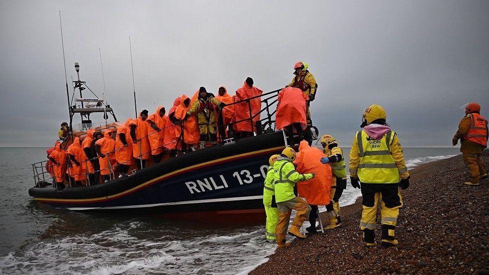 Migrants, picked up at sea attempting to cross the English Channel, are helped ashore from an Royal National Lifeboat Institution (RNLI) lifeboat, at Dungeness on the southeast coast of England, on December 9, 2022