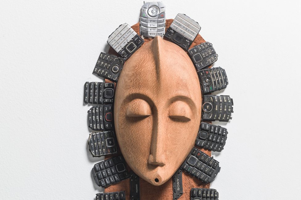 A Peter Oloya artwork, which features a traditional bride mask adorned with keypads of old mobile phones