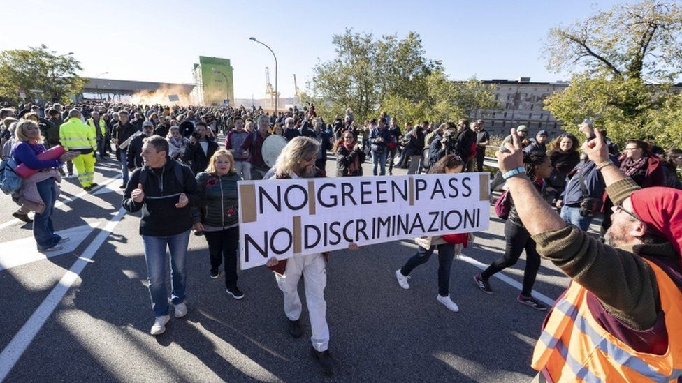 Докеры держат плакат с надписью «Нет Зеленого прохода - нет дискриминации» во время акции протеста против Зеленого прохода в порту Триеста, северная Италия, 15 октября 2021 г.