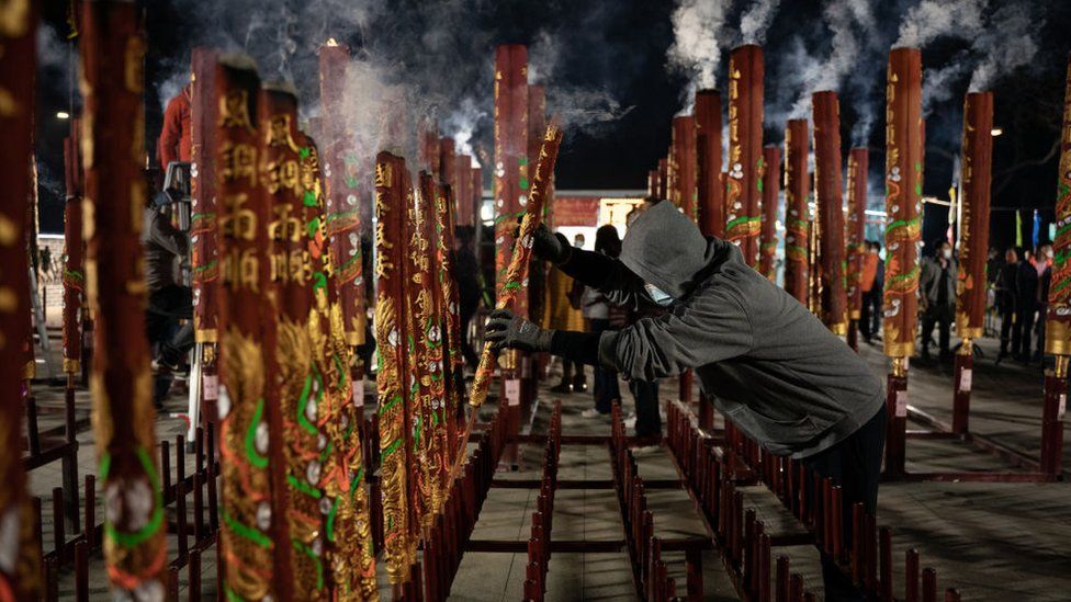 A man makes an offering of joss sticks at a temple in Hong Kong