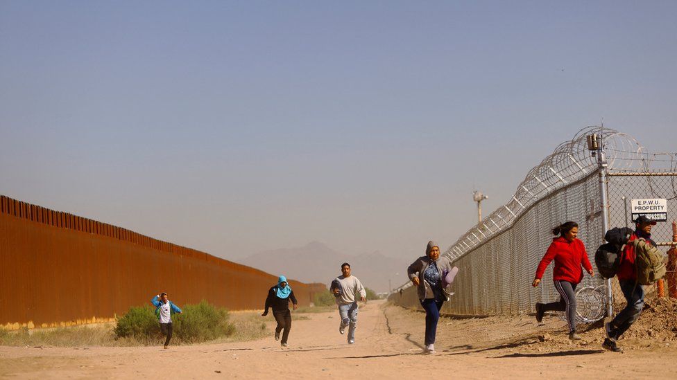 Migrants run from Border Patrol after crossing into El Paso, Texas