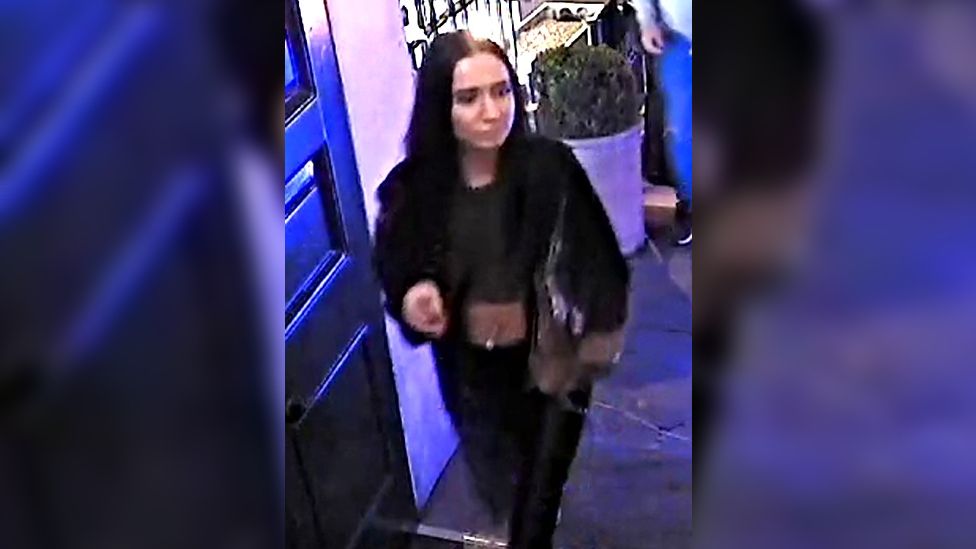 A woman with long dark hair seen leaving a bar wearing a black jacket, a black crop top and black skinny jeans, carrying a bag under her arm