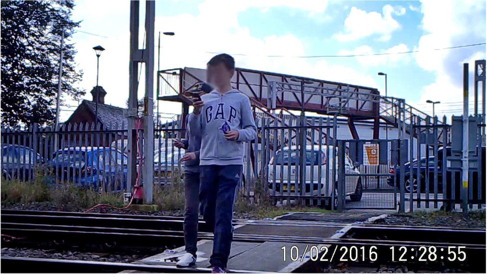 Children on the rail crossing on their mobile phones