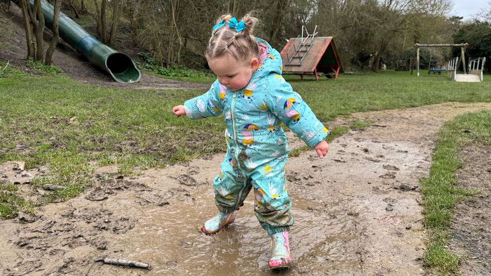 Esmee jumping in a puddle in a park