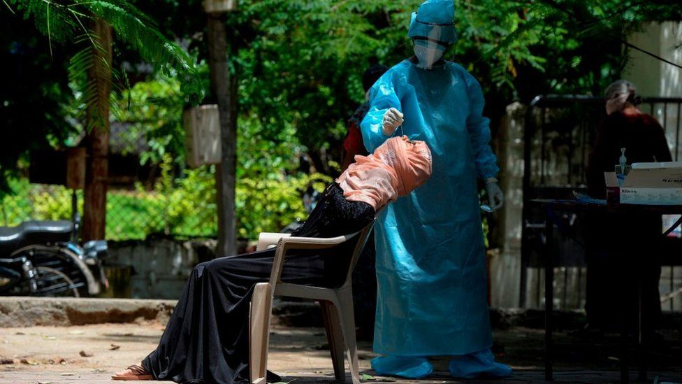 A health worker wearing Personal Protective Equipment (PPE) collects a swab sample from a woman for a free Covid-19 coronavirus test at a Municipal Corporation park in Hyderabad on August 31, 2020.
