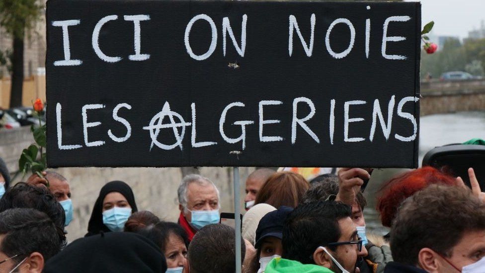 Placard saying: "Here we drown Algerians" seen at a remembrance ceremony to mark the 59th anniversary of the 1961 Paris massacre at the Pont Saint-Michel bridge over the River Seine in Paris, France - 17 October 2020