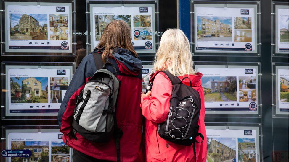 Two women look at homes for sale at estate agents