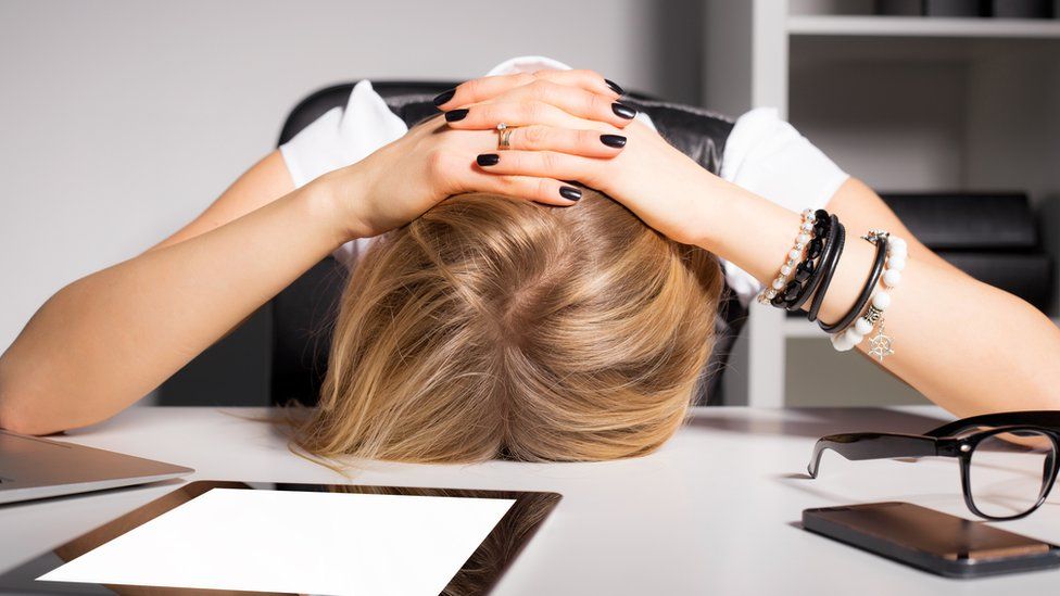 Woman resting her head on her office desk
