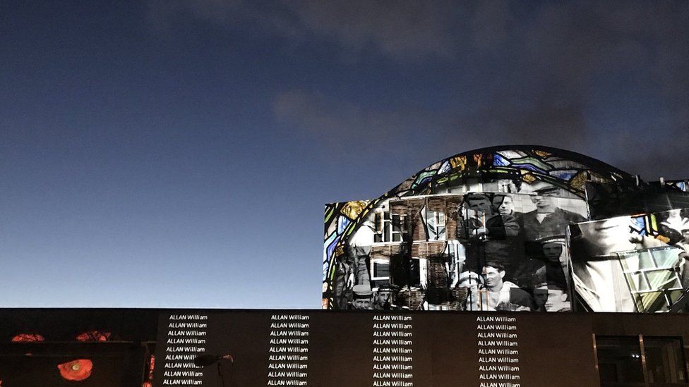 Names and photos projected on to the side of the Scottish Parliament building.