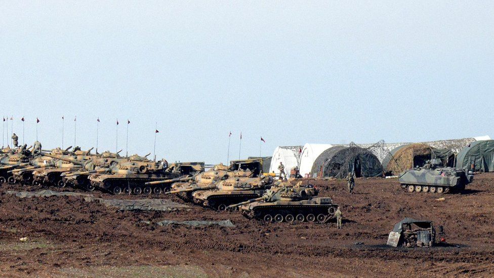 Turkish Army vehicles and tanks wait near the Syrian border in Suruc on February 23, 2015