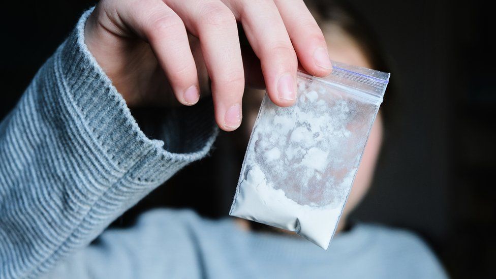 Woman holds packet of white narcotic