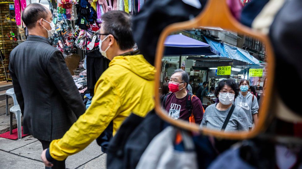 Las personas que usan máscaras protectoras caminan por un mercado en Hong Kong