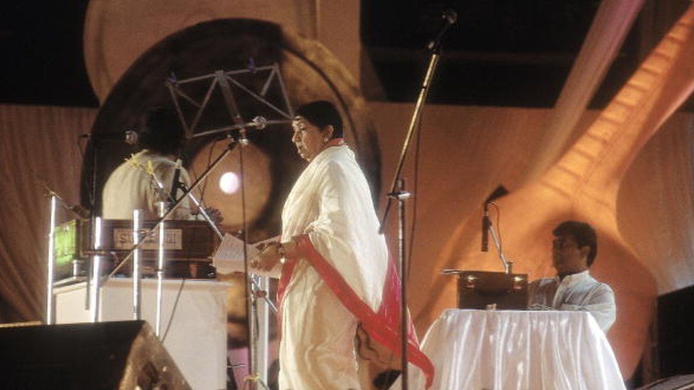 Лата Мангешкар, певица, записывающая свою песню в студии (Болливуд, боковой профиль