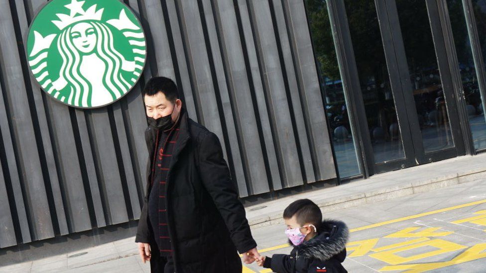 Man with child walks past closed Starbucks in China