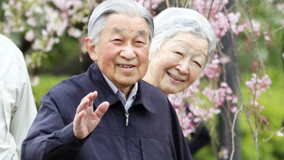 Japan's Emperor Akihito (L) and Empress Michiko walk among cherry blossom in Tokyo (April 2019)