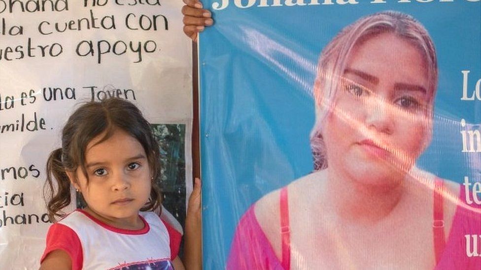 A girl stands next to the placard asking for the release of Johana Flores