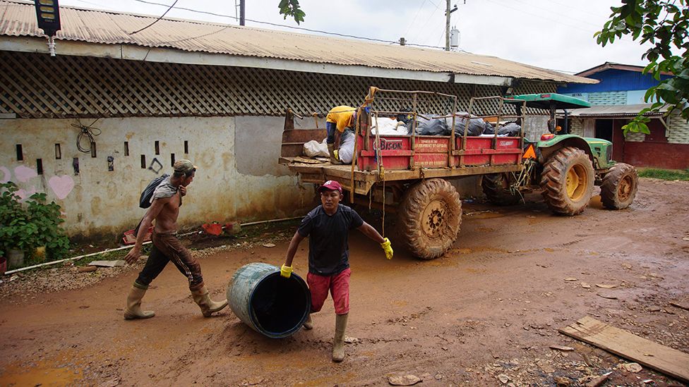 Мусорщики собирают мусор в Порт-Каитума, Гайана, 21 сентября 2022 года, перед мусоровозом на дороге.