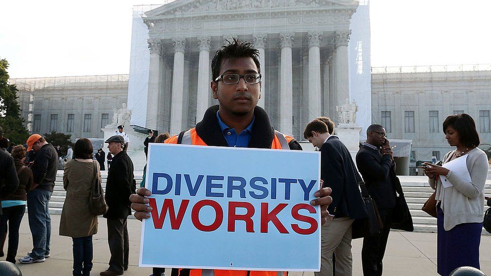 Мужчина держит плакат с надписью «Разнообразие работает» перед зданием Верховного суда США 10 октября 2012 года.