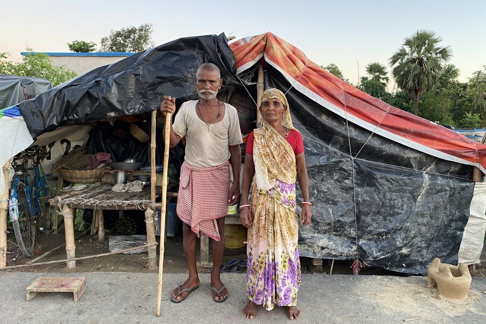 A elderly standing in front of their temporary tent
