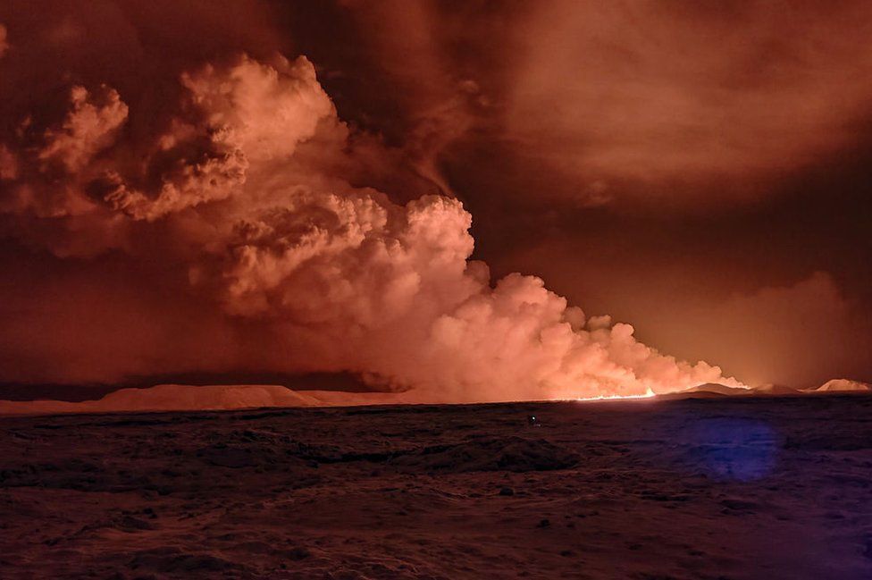 Smoke is billowing as the lava colour the night sky orange from an volcanic eruption on the Reykjanes peninsula 3 km north of Grindavik, western Iceland on December 18, 2023.