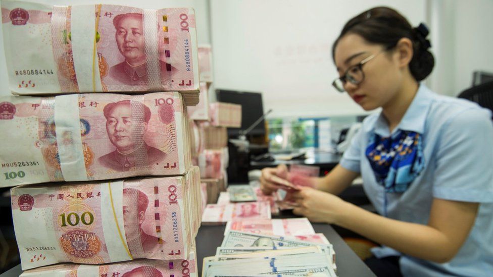 A Chinese bank employee counts 100-yuan notes and US dollar bills at a bank counter in Nantong in China's eastern Jiangsu province on August 28, 2019.