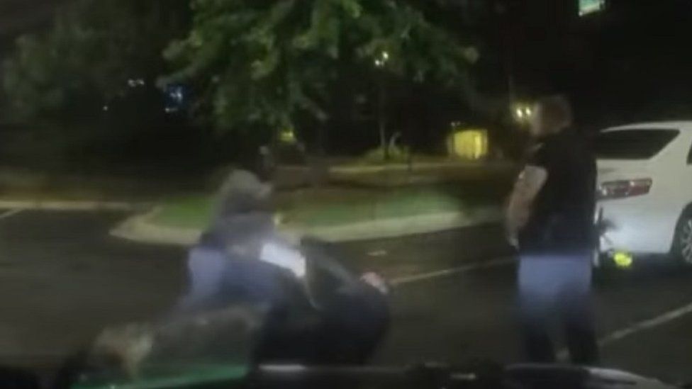 Two police officers grappling with Rayshard Brooks on the ground before he is shot