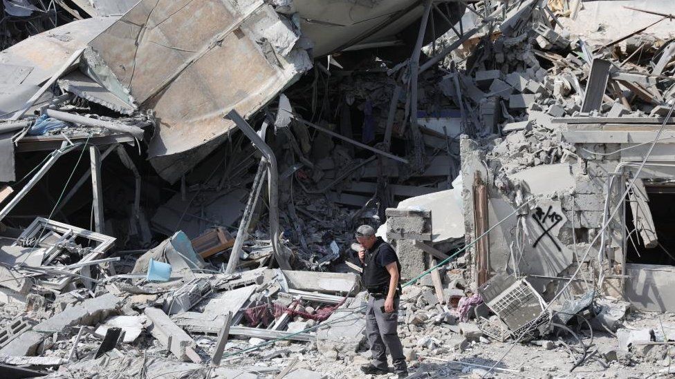A man standing in front of the wreckage of a building in Tel-Aviv, Israel