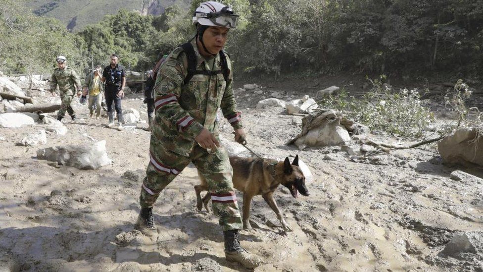 Колумбийский солдат ищет с собакой выживших после оползня в зоне, пострадавшей от оползня в Кветаме, Кундинамарка, Колумбия, 18 июля 2023 г.
