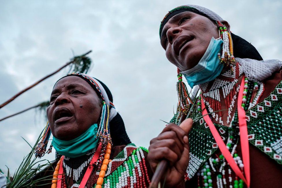 Women, wearing beaded clothing, sing and march during the festivities.
