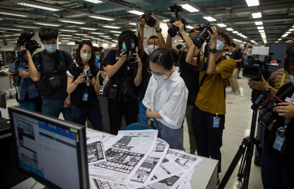 A proof reader surrounded by members of the media works in the newsroom of the Apple Daily newspaper on 17 June 2021