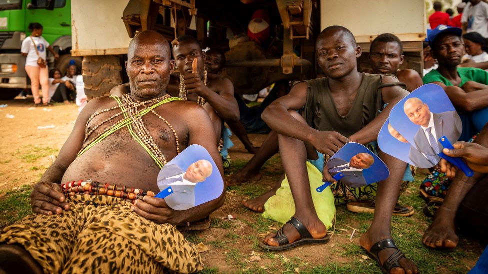 Supporters hold fans that have the face of CAR President Faustin Archange Touadera at a rally in Bangui, CAR - Friday 18 March 2022